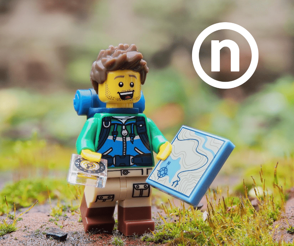 Lego figure dressed for hiking holding a map in a nature scene with Nelnet "N" in the upper right corner